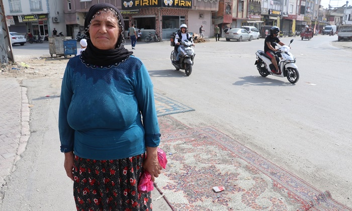 Adana'da tozdan rahatsız olan kadın yoldaki çukurları halıyla kapattı