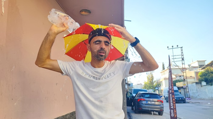 Aşırı sıcaklar nedeniyle kafasına taktığı şemsiye ile geziyor